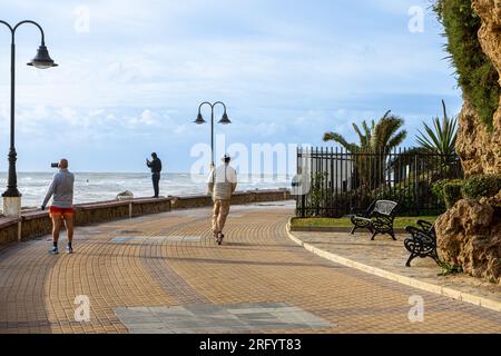 MALAGA, ESPAGNE - 10 FÉVRIER 2023 : personnes marchant sur la promenade pendant la tempête de la mer à Torremolinos, Malaga, Espagne sur 10 février 2023 Banque D'Images