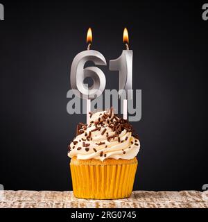 Bougie d'anniversaire numéro 61 - cupcake anniversaire sur fond noir Banque D'Images