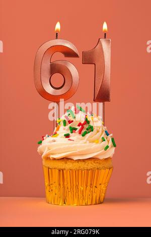 Gâteau d'anniversaire avec bougie numéro 61 - fond fusion corail Banque D'Images