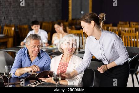 Femme serveur prenant la commande d'un couple âgé au restaurant Banque D'Images