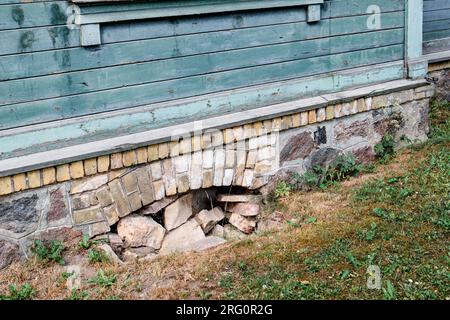 La fenêtre du sous-sol d'une vieille maison en pierre et brique remplie de pierres. Banque D'Images