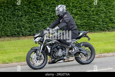 Whittlebury, Northants., Royaume-Uni - 6 août 2023. Moto Triumph Street Triple S noire 2022 traversant un village anglais. Banque D'Images