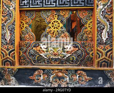Anciennes boiseries sculptées et peintes, y compris la roue bouddhiste à 8 rayons et des dragons sur une rampe en bois à Punakha Dzong, dans le Royaume du Bhoutan. Banque D'Images