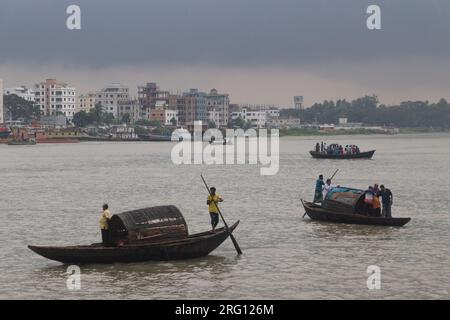 Narayanganj, Dhaka, Bangladesh. 7 août 2023. Les habitants traversent la rivière Shitalakhya par des bateaux en bois à Narayanganj, au Bangladesh, un jour de pluie. La saison de la mousson apporte de fortes précipitations au pays. En fait, environ 80% des précipitations annuelles du Bangladesh se produisent de juin à octobre, et à la fin de la saison de la mousson, près d'un tiers du pays est sous l'eau. Le Bangladesh est un pays très humide, recevant en moyenne environ 2 200 millimètres (mm) de précipitations par an. (Image de crédit : © Joy Saha/ZUMA Press Wire) USAGE ÉDITORIAL SEULEMENT! Non destiné à UN USAGE commercial ! Banque D'Images