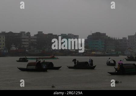 Narayanganj, Dhaka, Bangladesh. 7 août 2023. Les habitants traversent la rivière Shitalakhya par des bateaux en bois à Narayanganj, au Bangladesh, un jour de pluie. La saison de la mousson apporte de fortes précipitations au pays. En fait, environ 80% des précipitations annuelles du Bangladesh se produisent de juin à octobre, et à la fin de la saison de la mousson, près d'un tiers du pays est sous l'eau. Le Bangladesh est un pays très humide, recevant en moyenne environ 2 200 millimètres (mm) de précipitations par an. (Image de crédit : © Joy Saha/ZUMA Press Wire) USAGE ÉDITORIAL SEULEMENT! Non destiné à UN USAGE commercial ! Banque D'Images