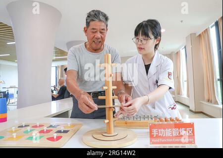HUZHOU, CHINE - le 7 AOÛT 2023 - un homme âgé est escorté par du personnel médical pendant une formation de réadaptation à la « Maison de réadaptation », une communauté Banque D'Images