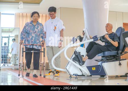 HUZHOU, CHINE - le 7 AOÛT 2023 - un homme âgé est escorté par du personnel médical pendant une formation de réadaptation à la « Maison de réadaptation », une communauté Banque D'Images