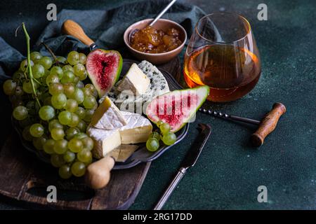Vue de dessus assortiment de collations délicieuses avec du fromage et servi sur une assiette placée au-dessus de la planche de bois avec des raisins et des figues et de la confiture Banque D'Images