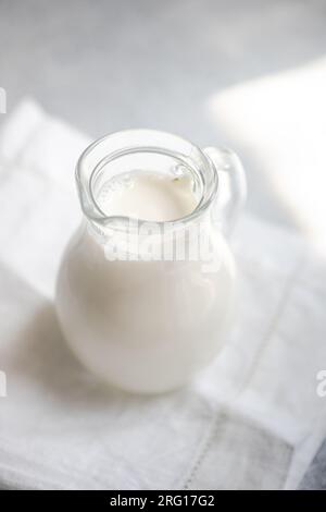 Angle élevé de lait de vache cru blanc dans un bocal en verre placé sur une serviette blanche sur fond flou Banque D'Images