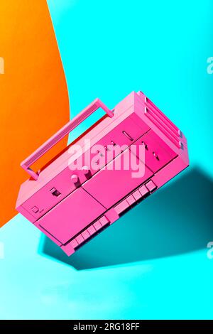 Système sonore rétro de boombox de couleur rose placé sur fond de couleurs bleu et jaune vif Banque D'Images