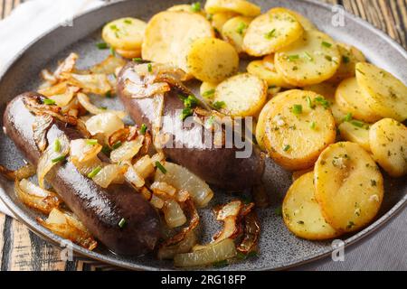Pudding noir maison avec des oignons frits avec un plat d'accompagnement de pommes de terre gros plan sur une assiette sur la table. Horizontal Banque D'Images