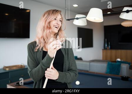 Femme riant hors de la caméra tout en craie queue de billard Banque D'Images