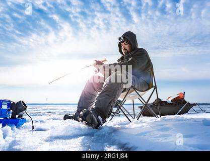 Pêcheur pêche sur glace sur le lac gelé Banque D'Images