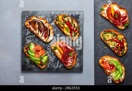 Ensemble de bruschetta assorties avec diverses garnitures pour les vacances sur la planche de pierre. Vue de dessus. Concept de nourriture de fête. Banque D'Images