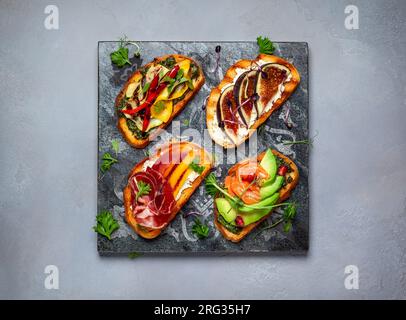 Ensemble de bruschetta assorties avec diverses garnitures pour les vacances sur la planche de pierre. Vue de dessus. Concept de nourriture de fête. Banque D'Images