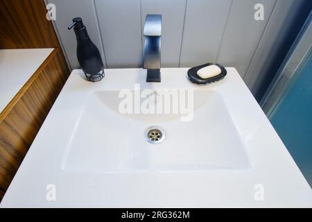 Les accessoires pour prendre un bain et se laver sont sur le lavabo blanc dans la salle de bain Banque D'Images