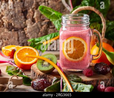 Smoothie sain avec des fruits, des baies, des fruits secs et des feuilles de blette dans une tasse de pot Mason sur fond en bois. Concept d'alimentation saine. Banque D'Images