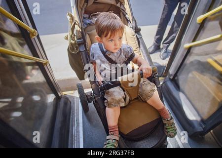 Le bébé est dans une voiture dans le bus, avec une mère adulte qui le pousse. Enfant garçon âgé de deux ans (deux ans) Banque D'Images