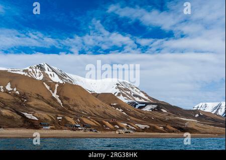 Des falaises enneigées s'élèvent derrière une petite colonie près de Longyearbyen sur la baie d'Adventfjorden.Longyearbyen, Île de Spitsbergen, Svalbard, Norvège. Banque D'Images