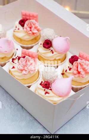 Coffret cadeau avec de beaux cupcakes roses décorés de mini barres de chocolat, meringue, framboise et fromage à la crème glaçage Banque D'Images