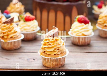 Magnifiques cupcakes au beurre de cacahuète, caramel salé et barre de chocolat sur fond de bois rustique Banque D'Images