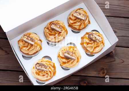 Magnifiques cupcakes au beurre de cacahuète, caramel salé et barre de chocolat sur boîte cadeau en carton Banque D'Images