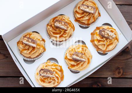 Magnifiques cupcakes au beurre de cacahuète, caramel salé et barre de chocolat sur boîte cadeau en carton Banque D'Images