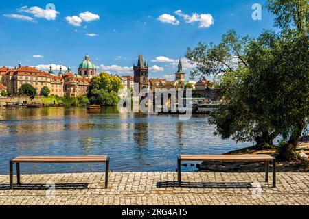 Deux bancs et le célèbre pont Charles sur la rivière Vltava sous le ciel bleu à Prague, République tchèque. Banque D'Images