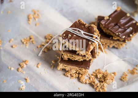 Barres ou carrés de flocons d'avoine à haute énergie, faits avec des flocons d'avoine, beurre d'arachide, miel, huile de coco, et des noix de cajou, garnies de chocolat. Banque D'Images