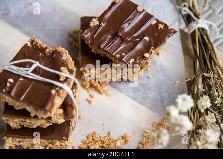 Barres ou carrés de flocons d'avoine à haute énergie, faits avec des flocons d'avoine, beurre d'arachide, miel, huile de coco, et des noix de cajou, garnies de chocolat. Banque D'Images