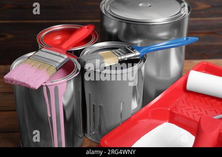 Boîtes de peintures, pinceaux et plateau avec rouleau sur table en bois, closeup Banque D'Images