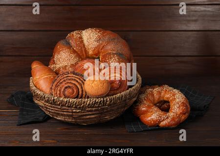 Panier en osier avec différentes pâtisseries savoureuses fraîchement cuites sur la table en bois Banque D'Images