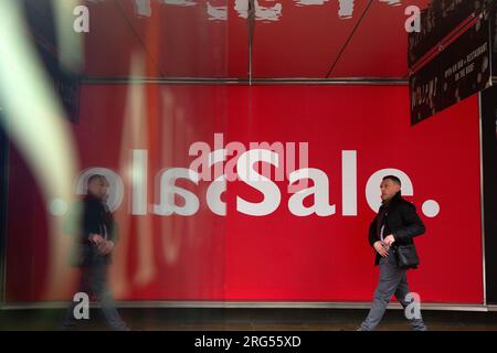 Un panneau de vente se reflète dans un mur d'arrêt de bus sur Oxford Street dans le centre de Londres, le jour de l'an. Banque D'Images