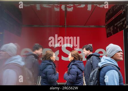 Un panneau de vente se reflète dans un mur d'arrêt de bus sur Oxford Street dans le centre de Londres, le jour de l'an. Banque D'Images