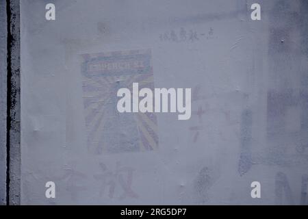 Le vieux graffiti vu sous la peinture blanche à Brick Lane. China Deviant, un groupe militant anti-Parti communiste chinois à Londres, peint des graffitis sur le mur controversé de Brick Lane. Un groupe d'étudiants chinois du Royal College of London (RCA) ont peint le mur en blanc avec les 12 valeurs fondamentales du socialisme pendant la Révolution culturelle au cours du week-end. Leurs actions ont suscité un vif débat entre les artistes locaux et les communautés chinoises et questionné sur la propagation de la propagande pro-chinoise. Le mur a été prétendu avoir été repeint par le conseil pour blanchir ce morni Banque D'Images