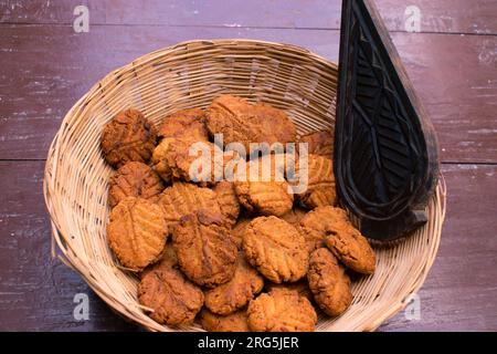 Thekua , un plat sucré indien ou une collation en bambou ou panier en bois ou tokri avec moule dans la table en bois. populaire à bihar jharkhand. Prashad in chhath Banque D'Images