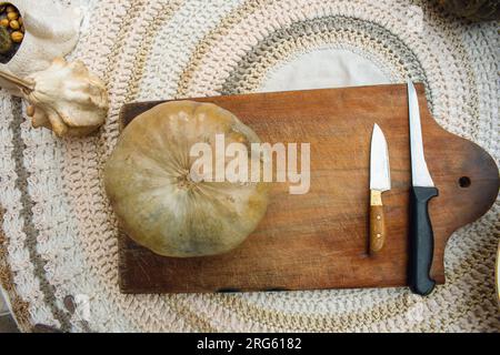 fond d'halloween, une citrouille et deux couteaux sur une planche à découper en bois, sur une table avec espace de copie Banque D'Images