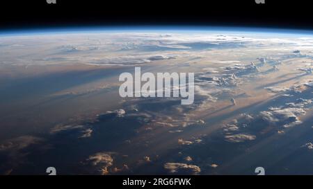 Le lever du soleil projette de longues ombres sur une mer nuageuse des Philippines, vue de l'espace. Banque D'Images