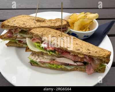 Club sandwich à base de poulet, jambon tomate et salade avec chips de pommes de terre Banque D'Images