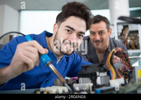 heureux jeune homme soud une puce dans un atelier Banque D'Images