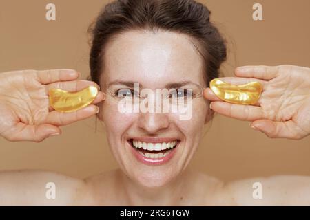 femme moderne heureuse avec des taches oculaires isolées sur fond beige. Banque D'Images