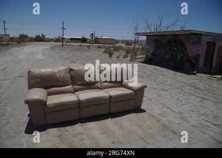 Canapé abandonné en mauvais état à Salton Sea California en 2015 devant un bâtiment abandonné couvert de grafitti. Banque D'Images