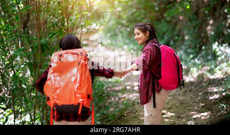 Deux randonneurs avec sacs à dos marchant dans la forêt profitant de la vue sur la vallée et prenant des photos. aidez-vous les uns les autres Banque D'Images