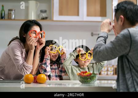 famille asiatique heureuse avec deux enfants s'amusant ensemble dans la cuisine à la maison Banque D'Images