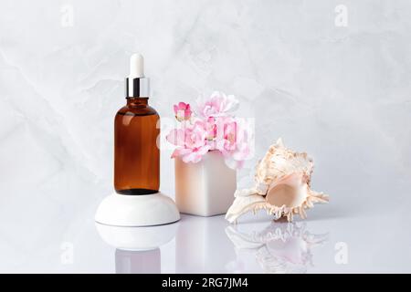 Sérum facial, ​​shell de mer. Bouteille en verre brun, fiole, bouquet de fleurs printanières roses. Huile de massage aromatique et fleur de cerisier. Cosm spa bio naturel Banque D'Images