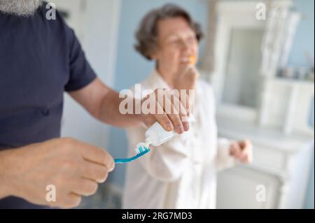 Vue rapprochée sur homme âgé poussant le dentifrice sur la brosse Banque D'Images