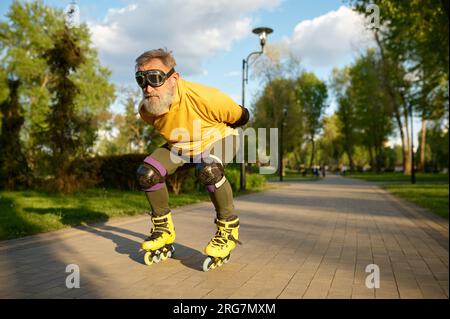 Homme âgé portant des lunettes drôles appréciant la course de vitesse sur des patins à roulettes Banque D'Images