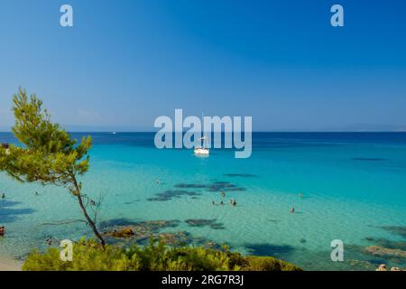 Kavourotrypes, Grèce - 14 août 2017 : vue d'un seul voilier et touristes profitant de la magnifique plage turquoise de rêve de Kavourotr Banque D'Images