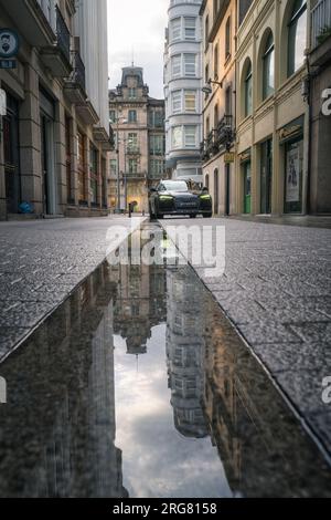 Bâtiments reflétés dans les flaques d'eau d'un canal de drainage sur les pavés d'une vieille rue de Lugo Galice Banque D'Images