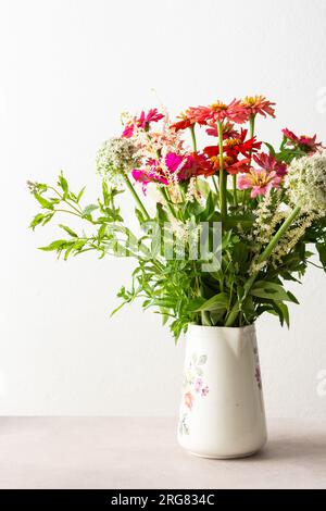 Bouquet d'été de Zinnia colorée, inflorescences d'oignon et brins de menthe, bouquet de fleurs sur la table près du mur, décoration de la maison avec des fleurs Banque D'Images